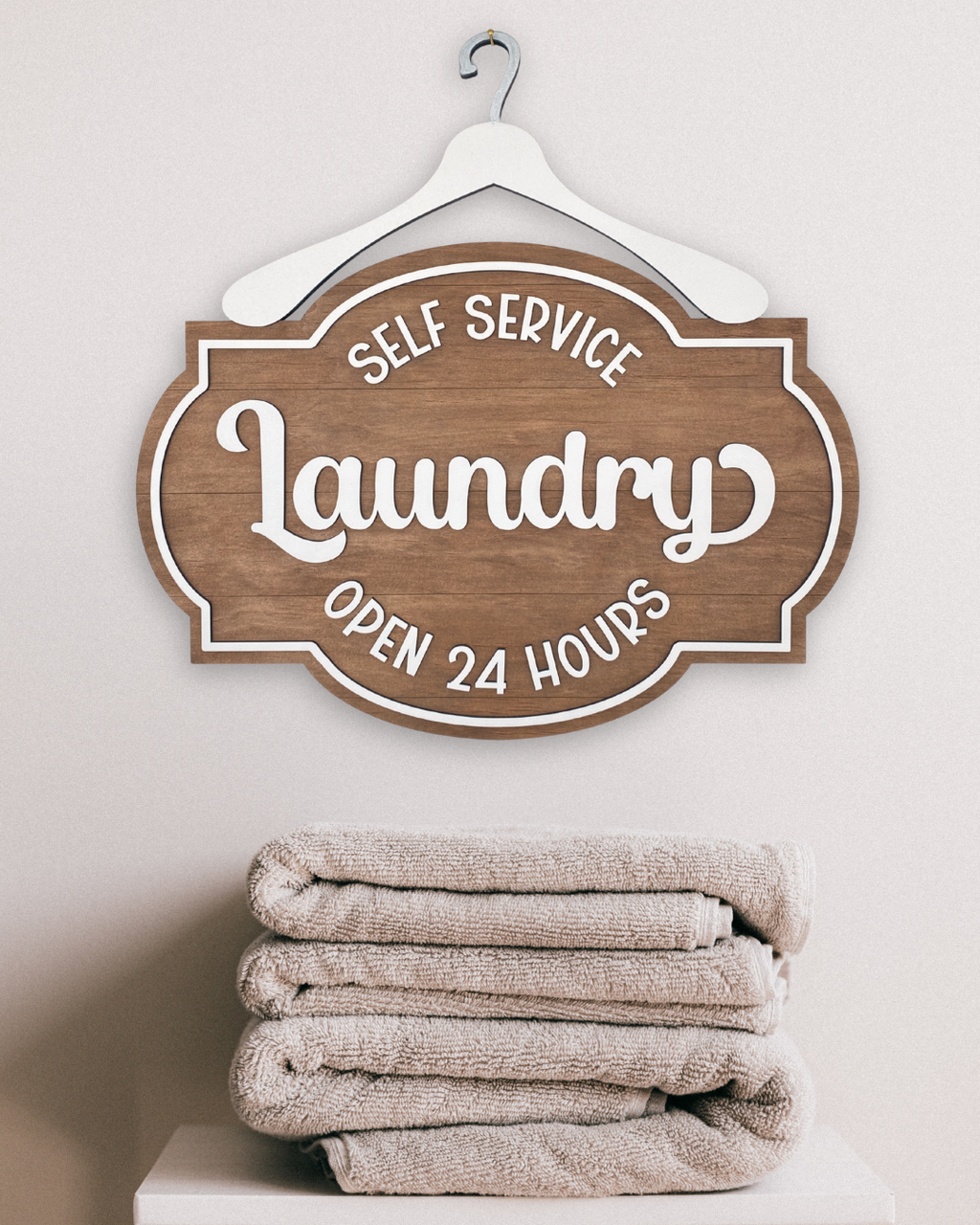Wooden sign with 'Self Service Laundry Open 24 Hours' text above folded towels on a white background