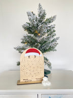 Wooden advent calendar placed next to a mini Christmas tree, in the shape of Santa Claus. Place cotton balls onto the sticky dots and fill out his beard each day of the advent.