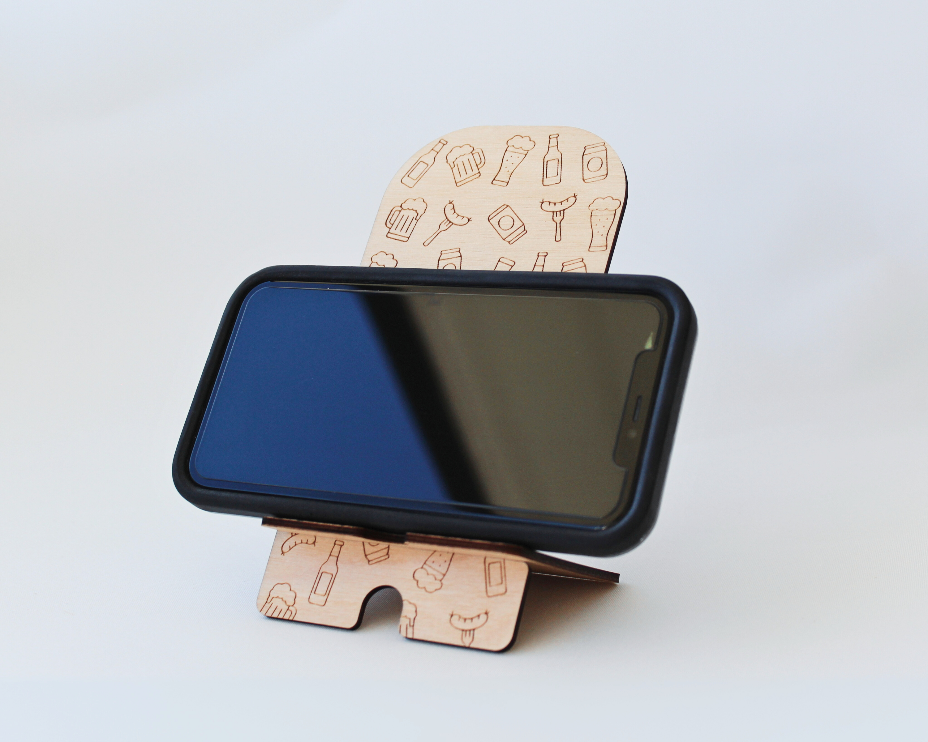 Wooden Phone Stand in the Beer & Sausages design against a white background, holding a cellphone in landscape mode.