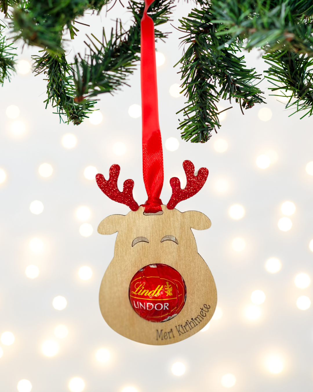 Laser-cut wooden Sweet-Nose Reindeer Ornament in red with a Lindt chocolate nose, engraved with the words Meri Kirihimete.