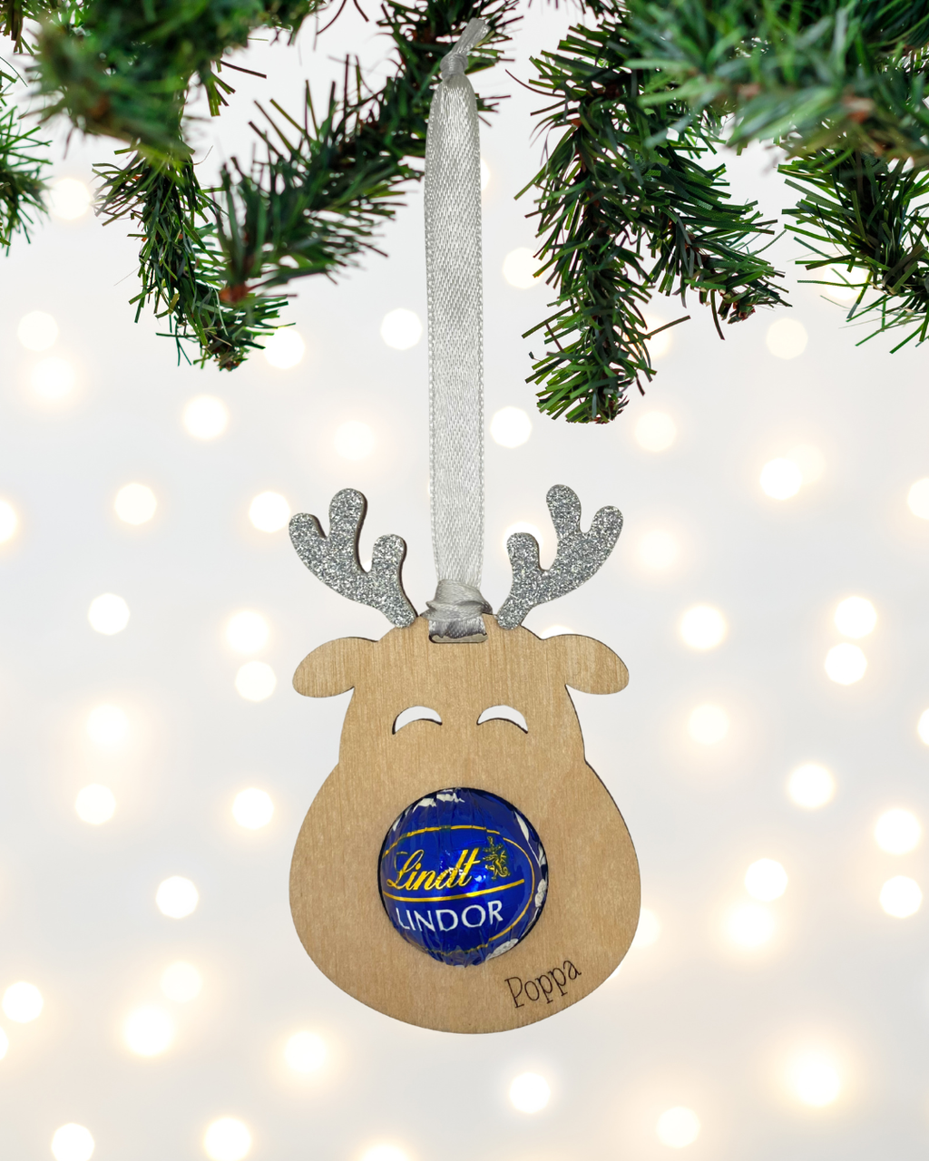 Laser-cut wooden Sweet-Nose Reindeer Ornament in silver with a Lindt chocolate nose, engraved with the word Poppa.